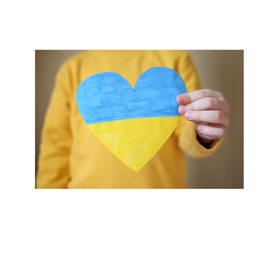 dziecko trzyma kartkę w kształcie serca z flagą Ukrainy