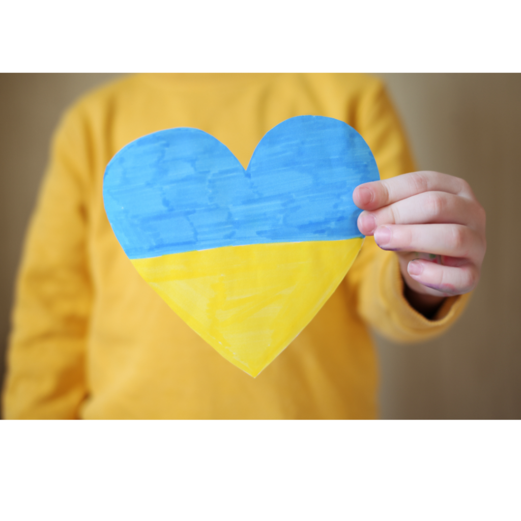 дитина піднімає картку у формі серця з прапором України
