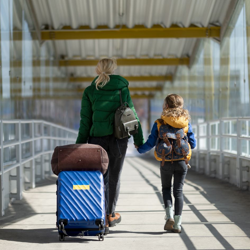 dziecko z kobietą niosącą walizkę z flagą Ukrainy
