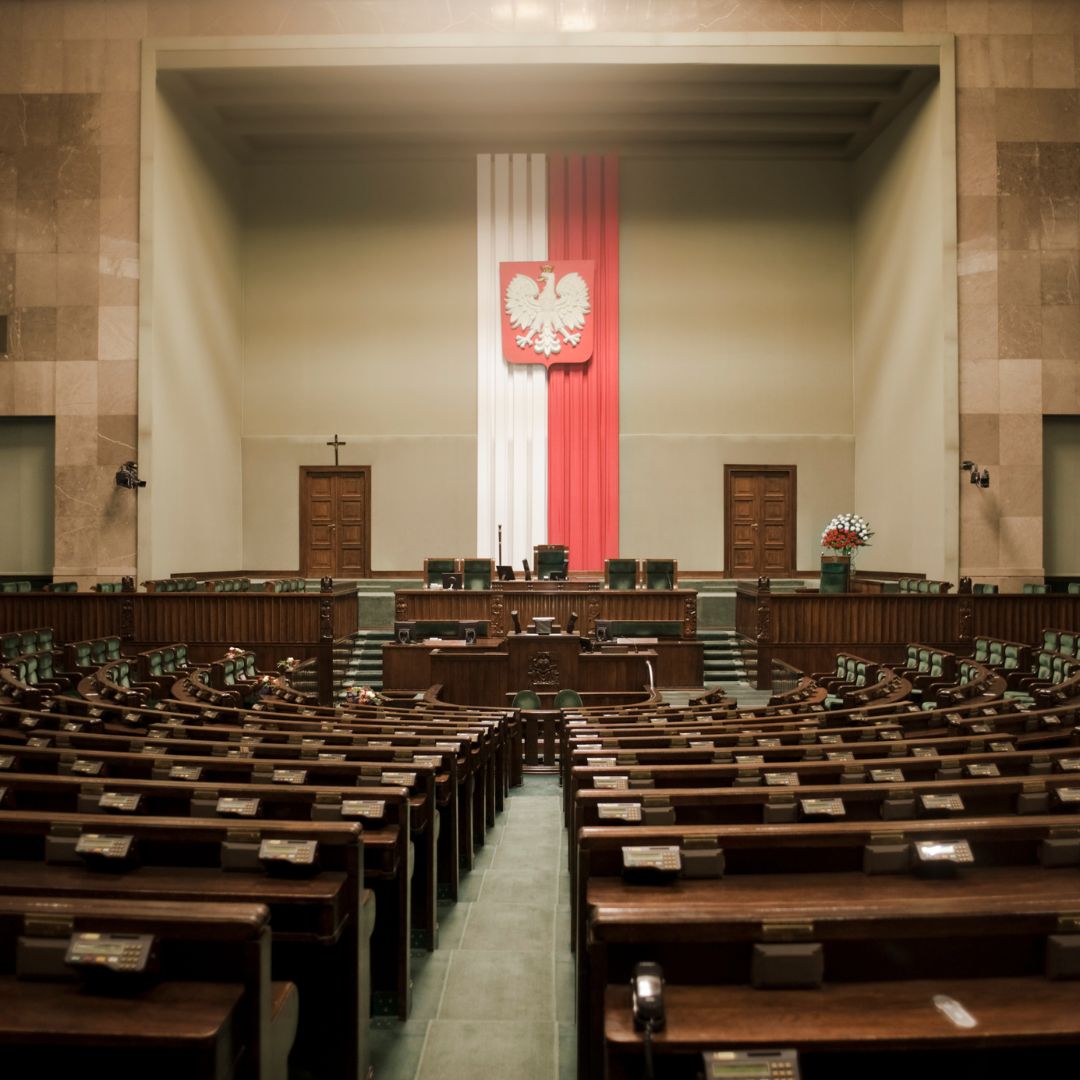 Pusta sala sejmowa RP z godłem Polski i flagą.
