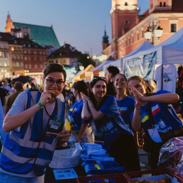 Grupa młodych ludzi, ochotników, pozuje do zdjęcia w Warszawie.