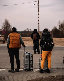 Ludzie z walizkami stojący na poboczu drogi.