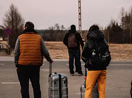 Ludzie z bagażami czekają przy drodze.