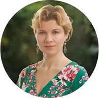 Portret kobiety w kwiecistej sukience, na tle zieleni.